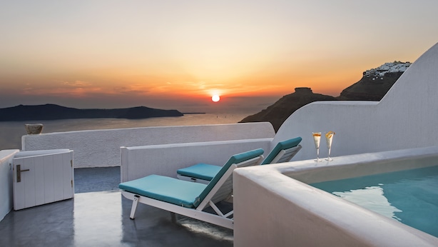 Un espace piscine aménagé sur le toit, avec des chaises longues et une vue sur le coucher de soleil sur la mer.