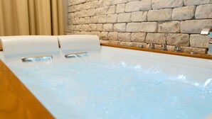 A modern spa bath with a stone wall backdrop and a wooden bench. - Resort & Winery Bosco De Medici  (Pompei)