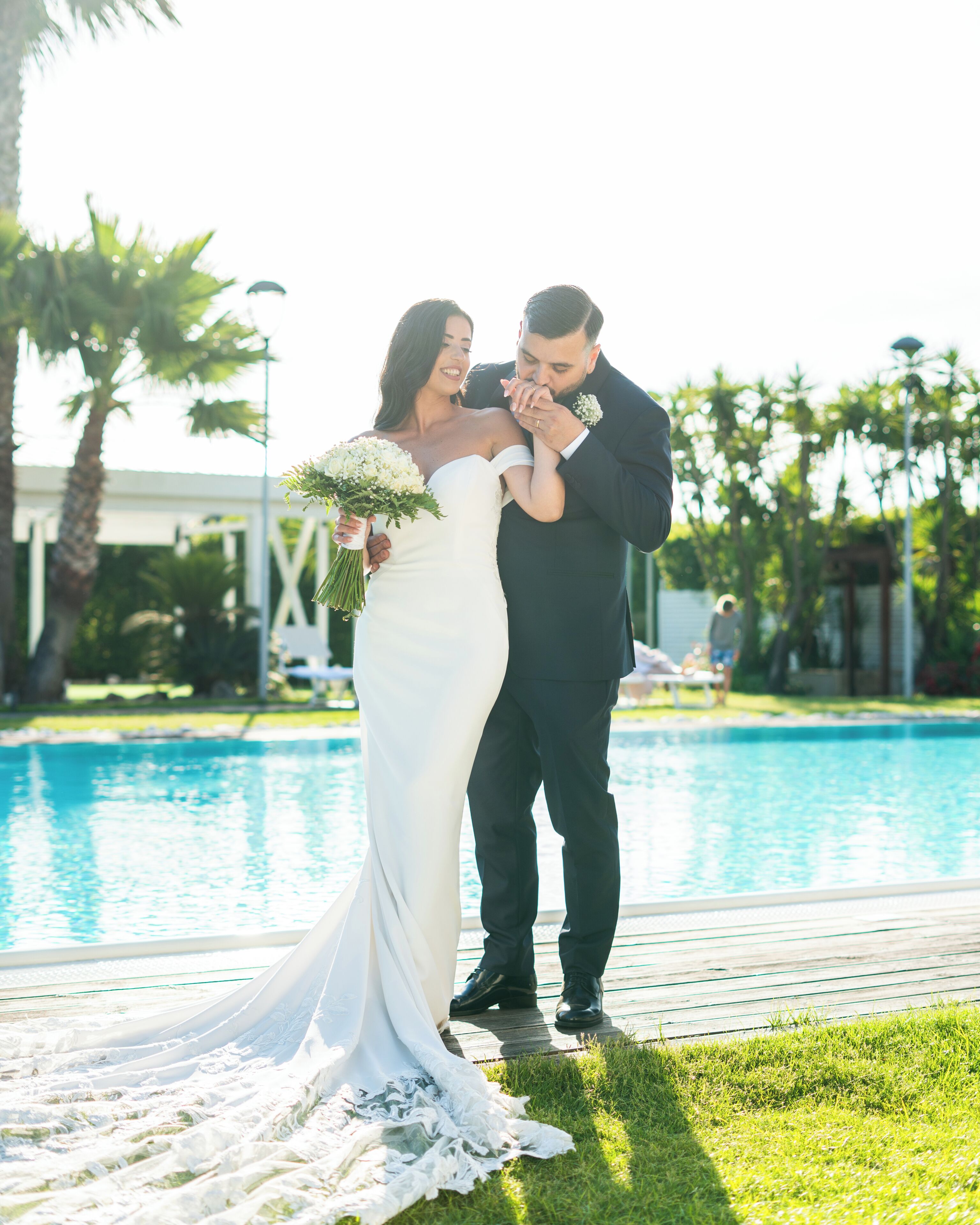 A couple standing by a pool with a clear view of the water and surrounding greenery.