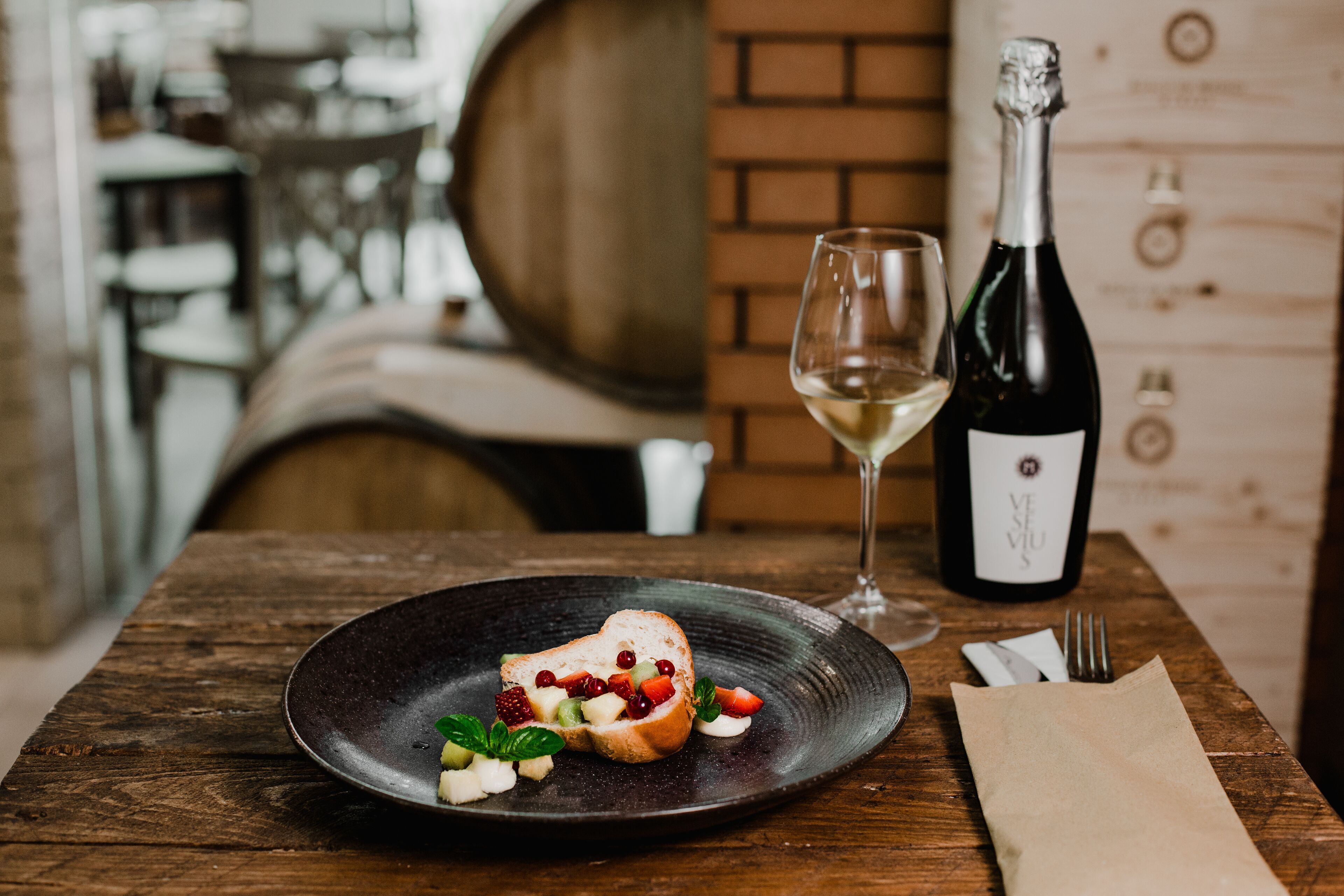 Une table en bois avec une assiette de nourriture, une bouteille de vin et un verre de vin.