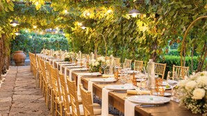 An outdoor dining area with tables set for a meal, surrounded by greenery and string lights. - Resort & Winery Bosco De Medici  (Pompei)