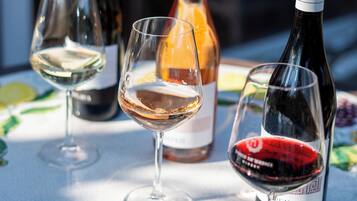 A table with wine glasses and bottles, a patterned tablecloth, and a clear view of the sky.