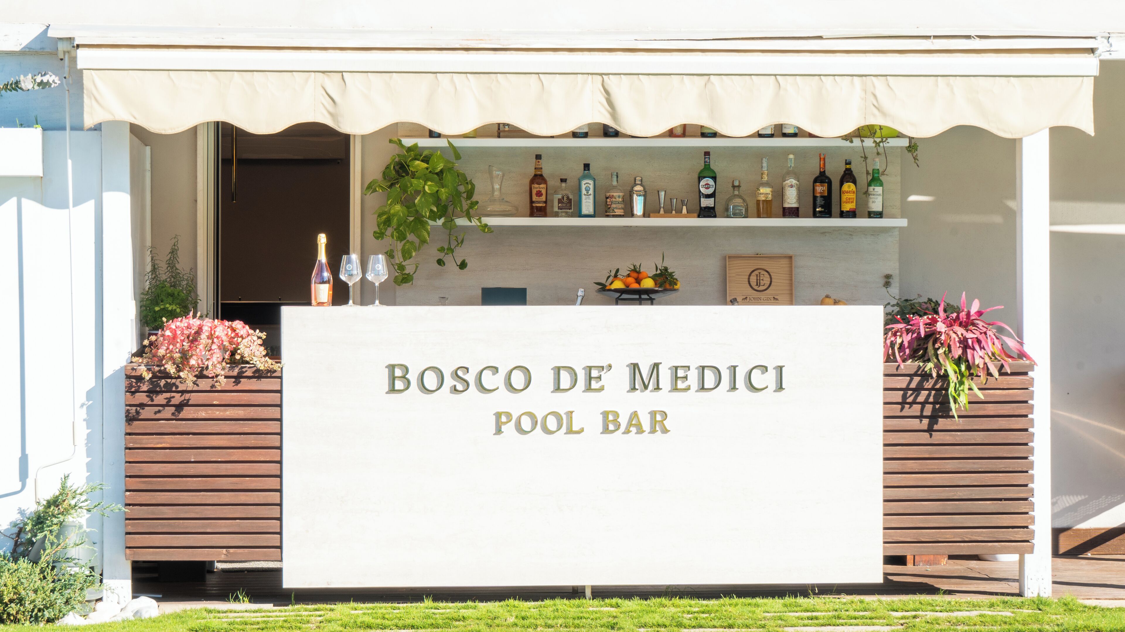 A pool bar named "BOSCO DE' MEDICI" with a variety of liquor bottles displayed on shelves and a signboard.