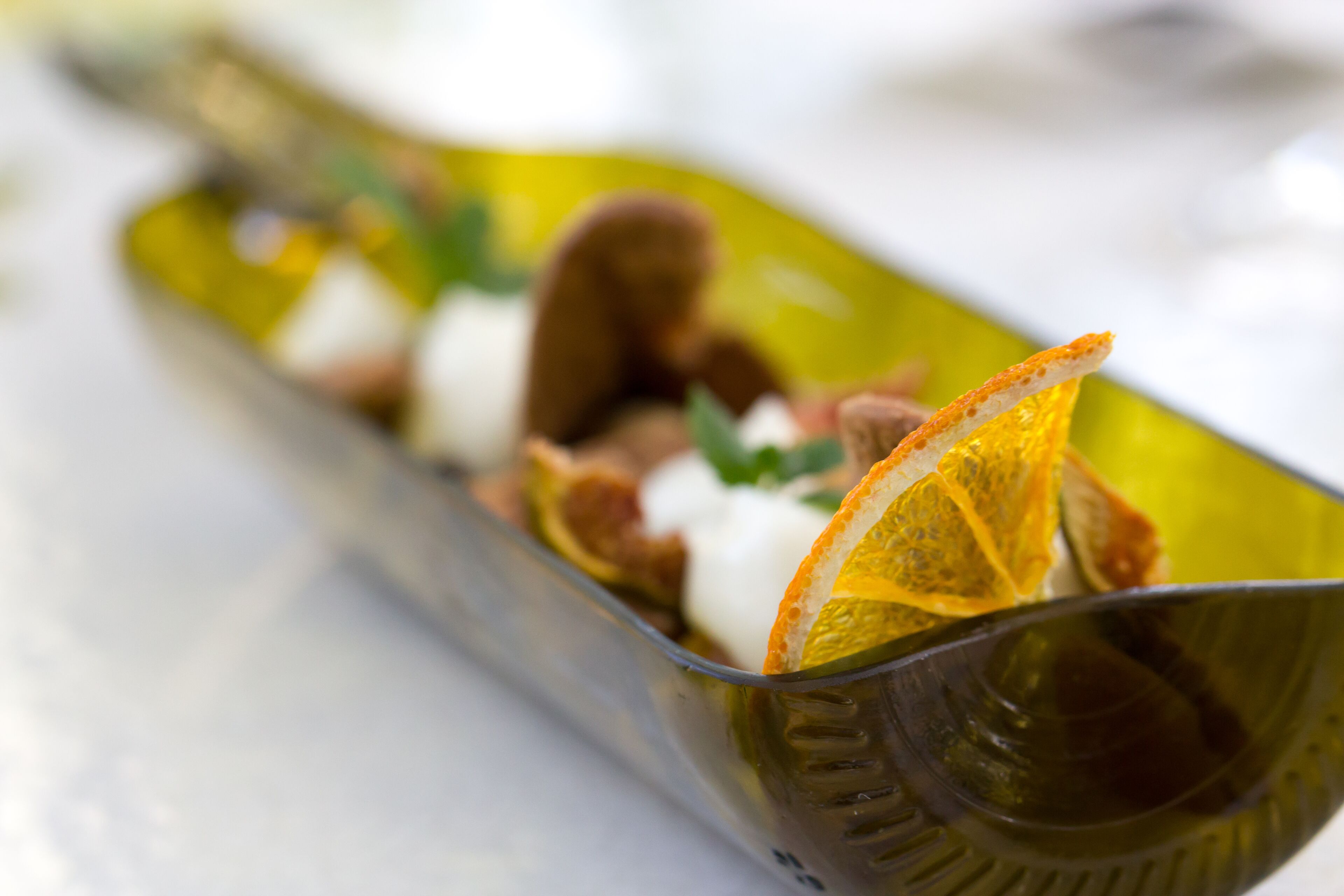 A glass dish with food items, including what appears to be a slice of orange and some nuts.