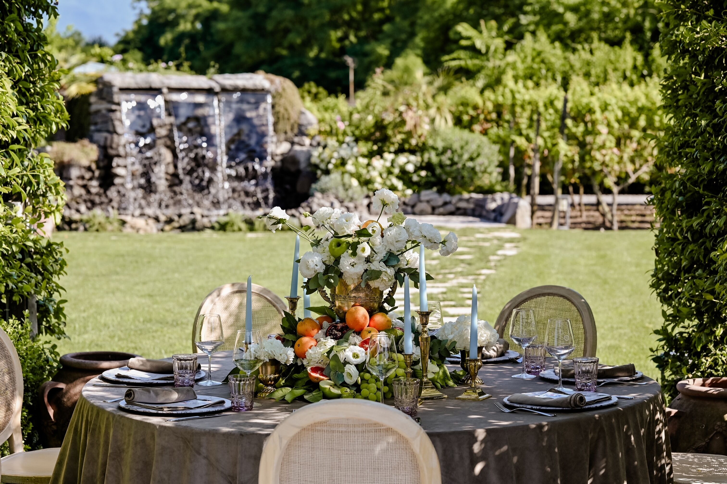 A table set outdoors with a floral centerpiece, glasses, and plates.