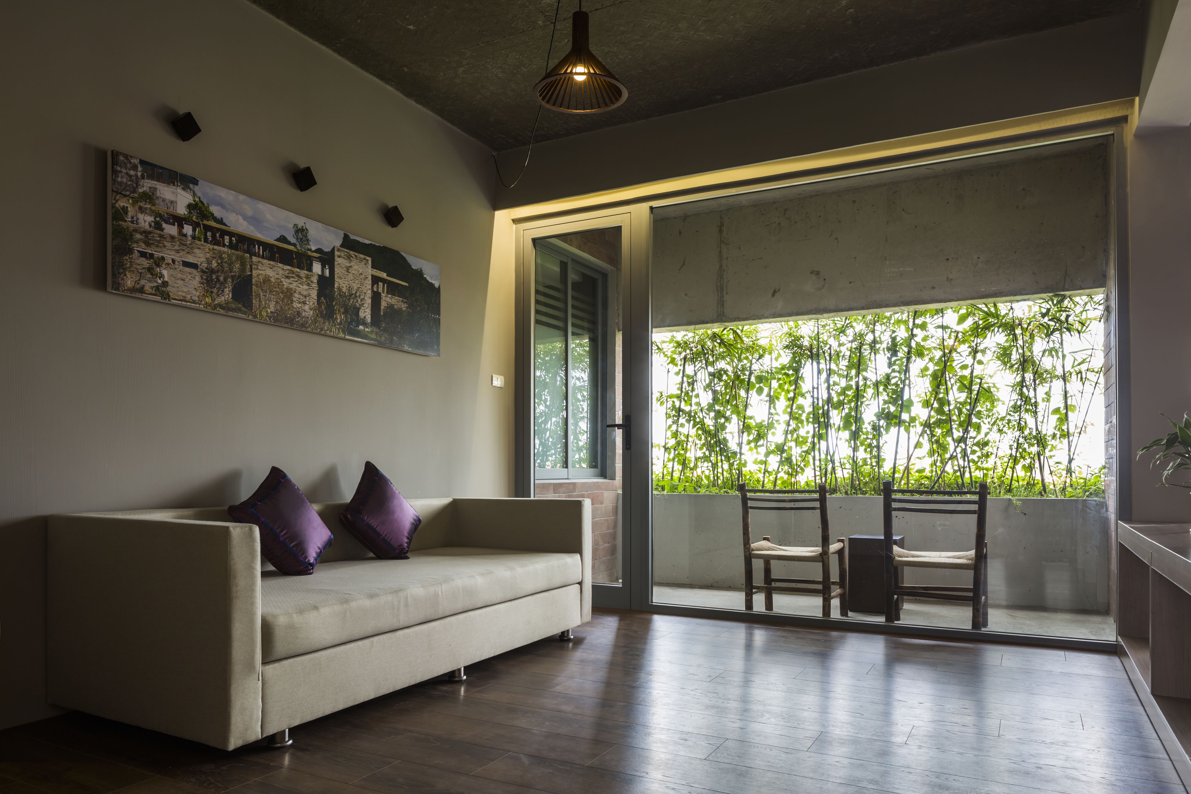 Una sala de estar moderna con un sofá, dos sillones, un ventanal con vistas a zonas verdes y un cuadro en la pared.