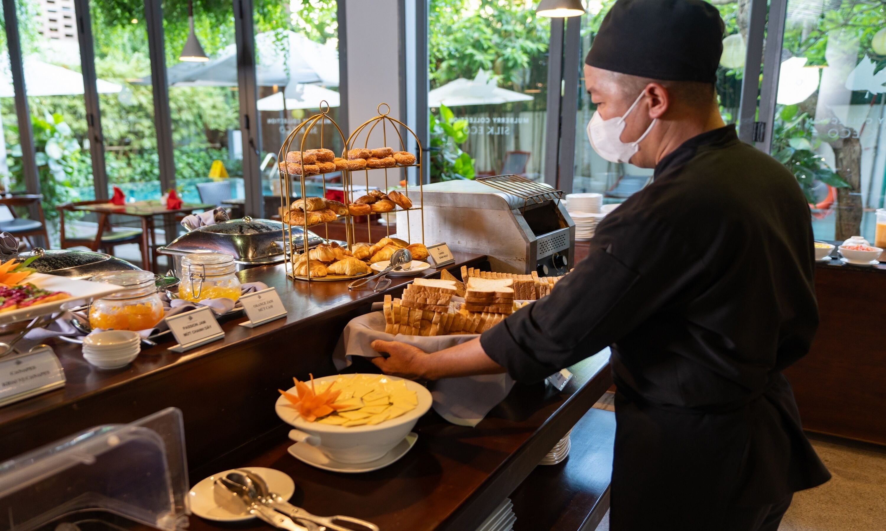 A buffet counter with various food items and a staff member serving.