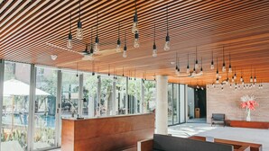 Un vestíbulo moderno con techo de madera, ventanas amplias, un mostrador de recepción y zonas de estar.