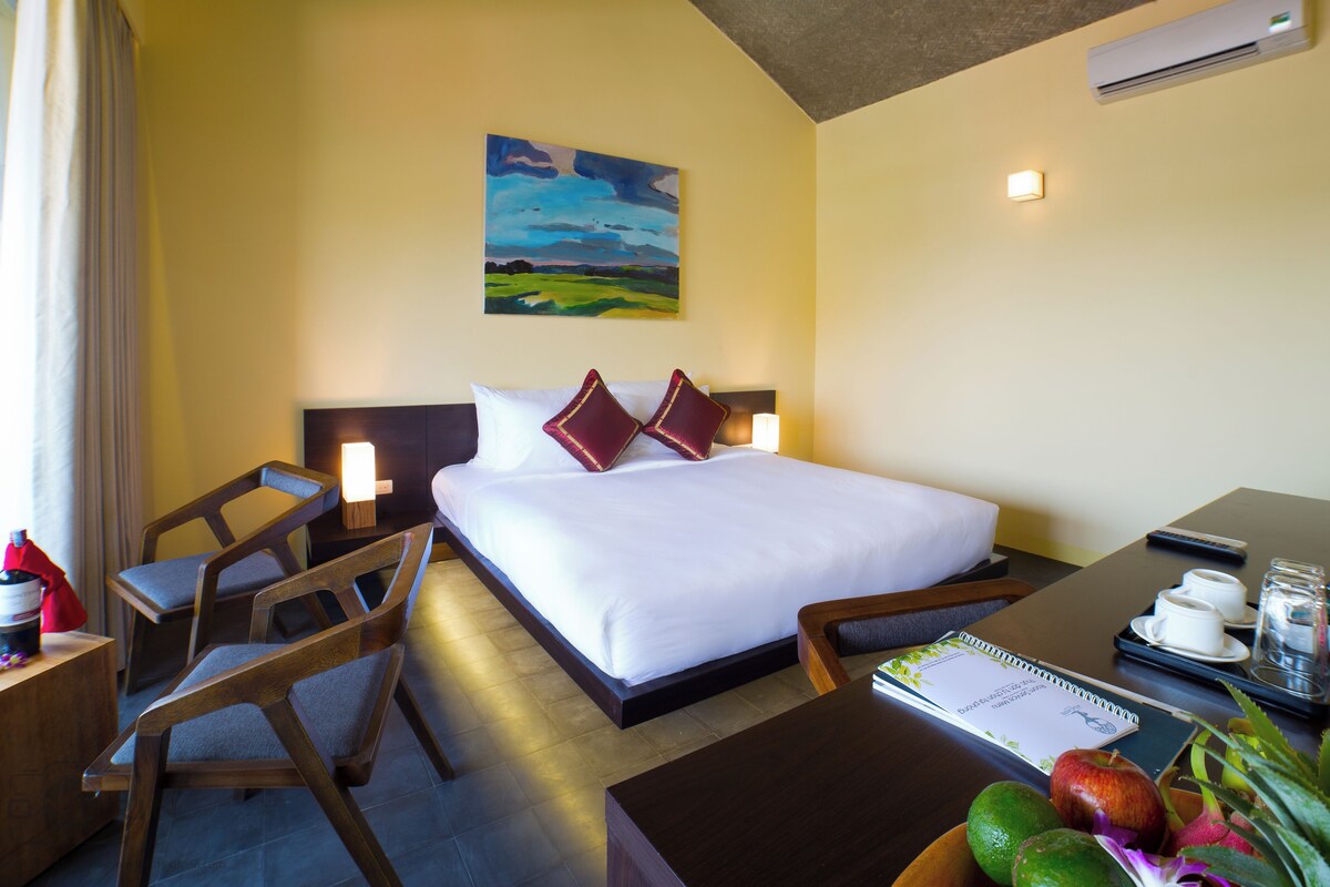 Una habitación de hotel con cama, mesitas de noche, escritorio y silla.