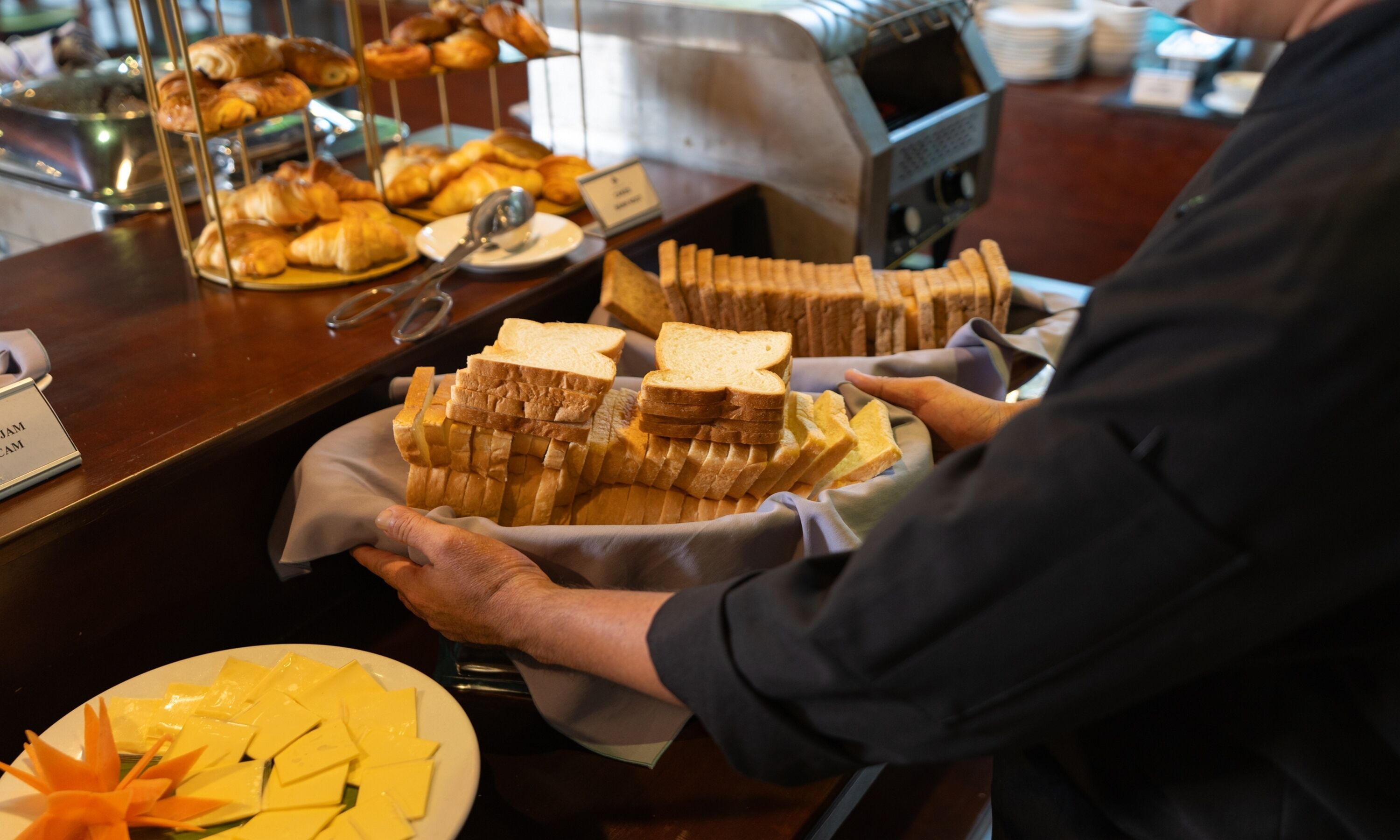 Mostrador de buffet con diversos alimentos, como pan, pasteles y queso.