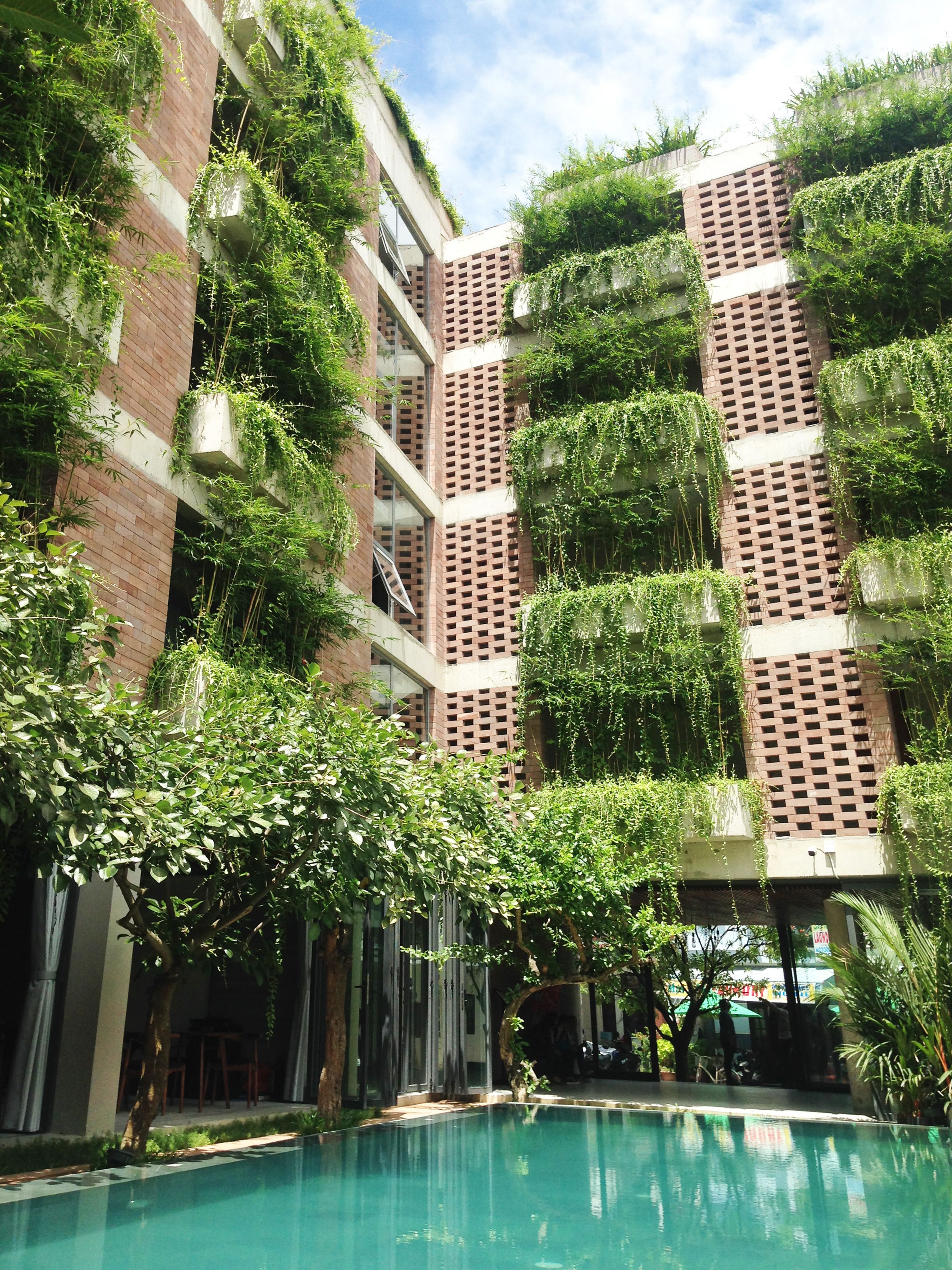 A modern building with a pool, surrounded by lush greenery and trees.