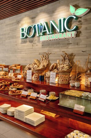 Zona de bufé con diversos alimentos y cestas que indican 'Pastel Decorado' y 'Mantequilla de Queso'.
