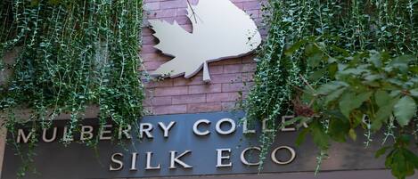 A sign for Mulberry College Silk Eco with a stylized bird logo.