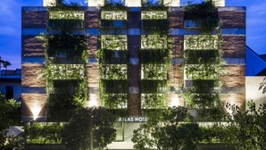 Un hotel con fachada moderna que presenta jardines verticales y una entrada destacada.
