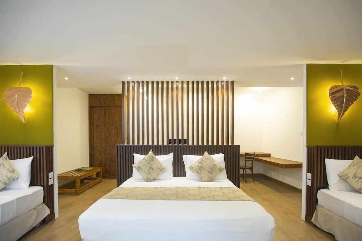 A hotel room with a large bed, two bedside tables, a wooden headboard, and a wall-mounted light fixture.