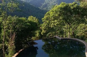 A circular water feature surrounded by lush greenery and trees. - Birds Park Polgahawela (Alawwa)