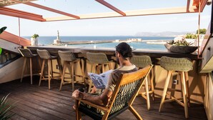 Una persona sentada a una mesa de madera con vista al mar y un faro.