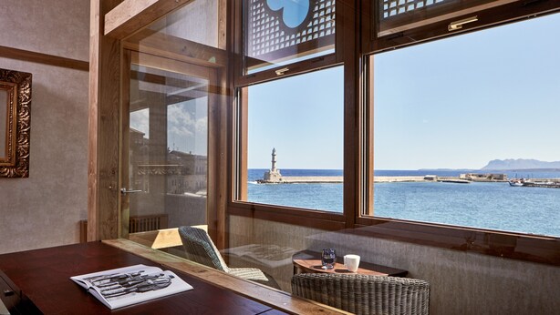 Una habitación con vistas al mar, una mesa con una revista y una silla de mimbre.