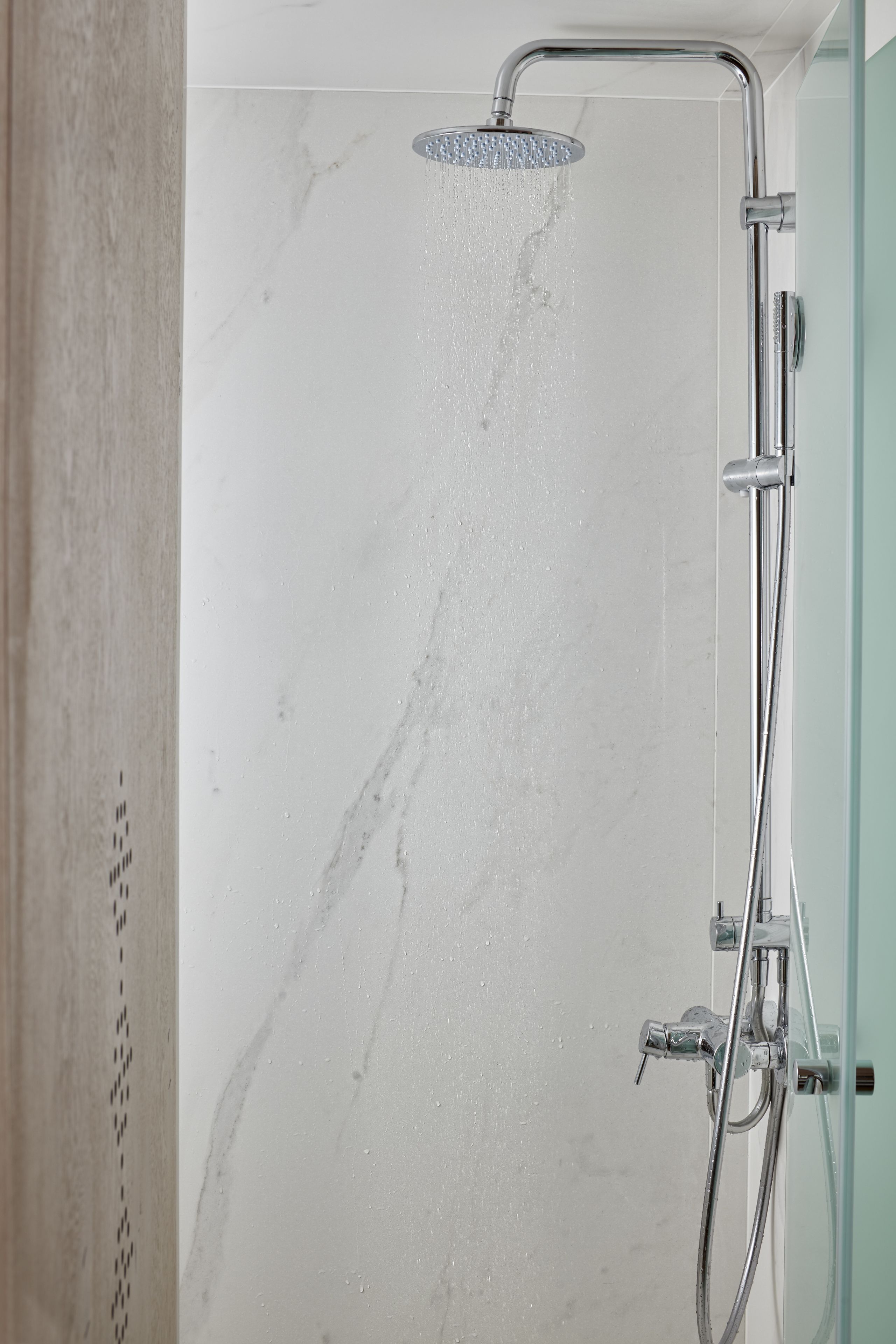 Une douche équipée d’un pommeau de douche à effet pluie et d’un pommeau de douche portatif.