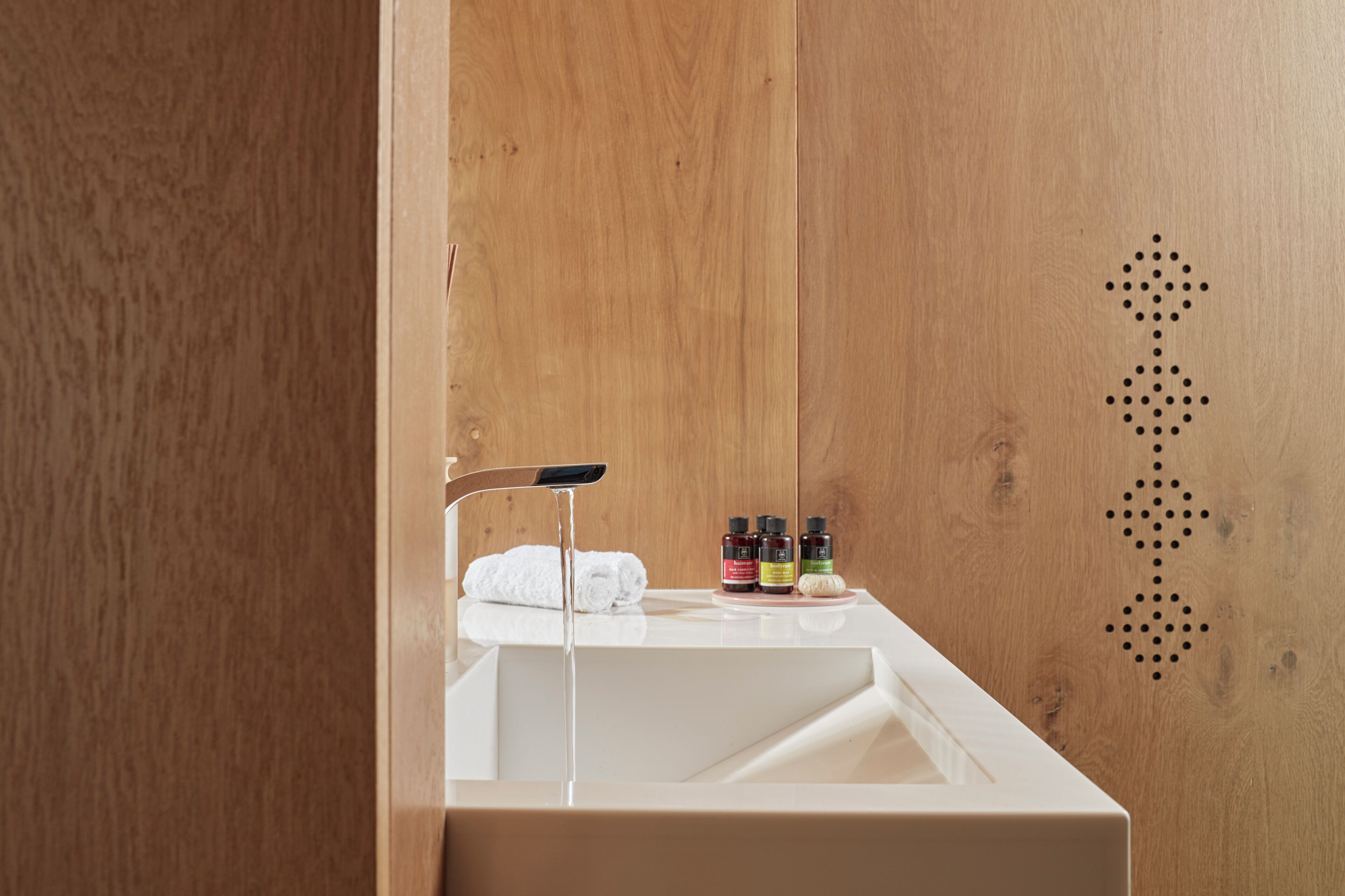 A bathroom with a wooden wall, a white sink, and a towel.