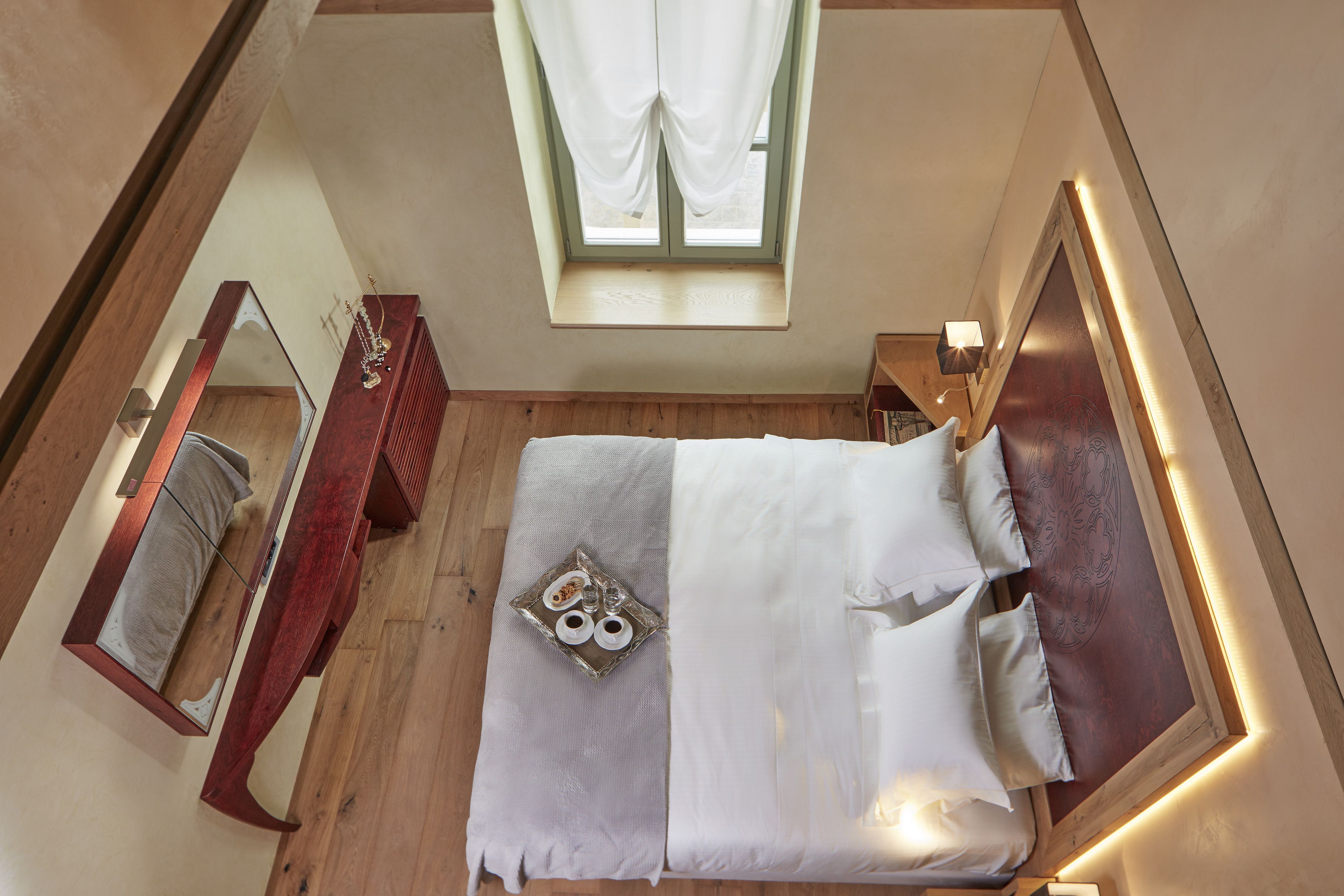 A bedroom with a bed, a dresser, a mirror, and a window with curtains.