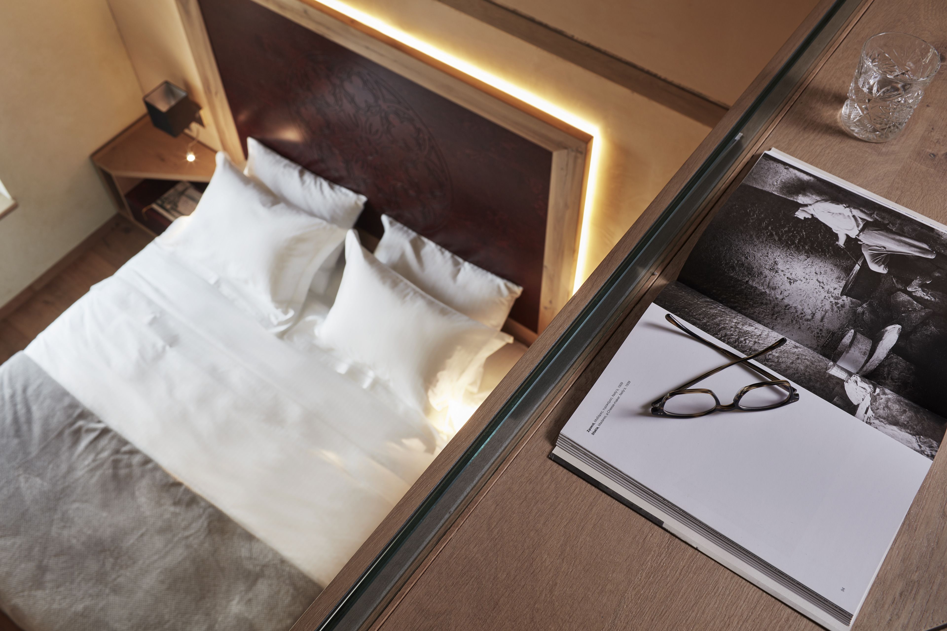 A neatly made bed with white linens, a wooden headboard, and a bedside table with a lamp.