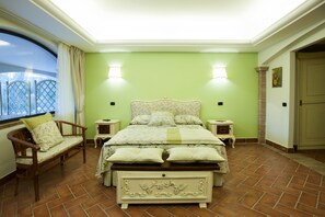A bedroom with a bed, two bedside tables, a chair, a window with curtains, and a door. - La Vignola Country Hotel (Ceprano)