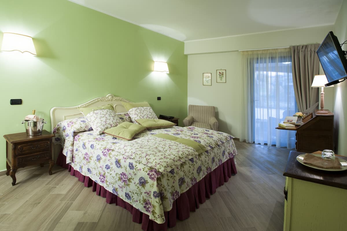 A bedroom with a bed, bedside tables, a television, and a window with curtains.