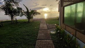 Ein Weg, der zu einem Gebäude führt, mit Blick auf den Sonnenuntergang über dem Wasser.