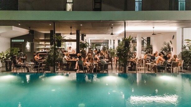 Un área de piscina interior con varias opciones de asientos y una barra de bar al fondo.
