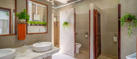 A modern bathroom with two sinks, a toilet, and a shower area.