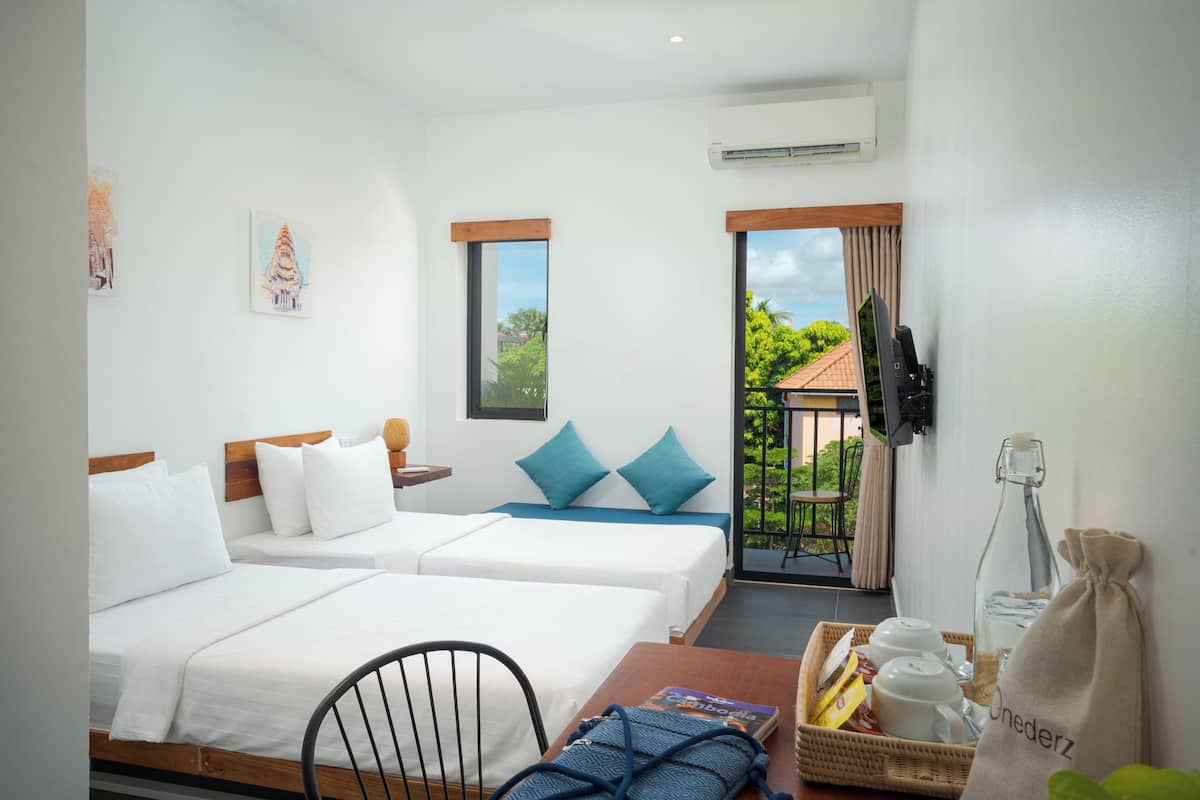 Habitación de hotel con dos camas, televisión, ventana con vistas y balcón.