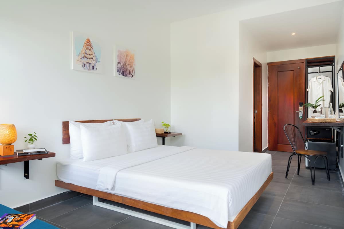 Una habitación de hotel moderna con una cama grande, un escritorio con una silla y obras de arte en las paredes.