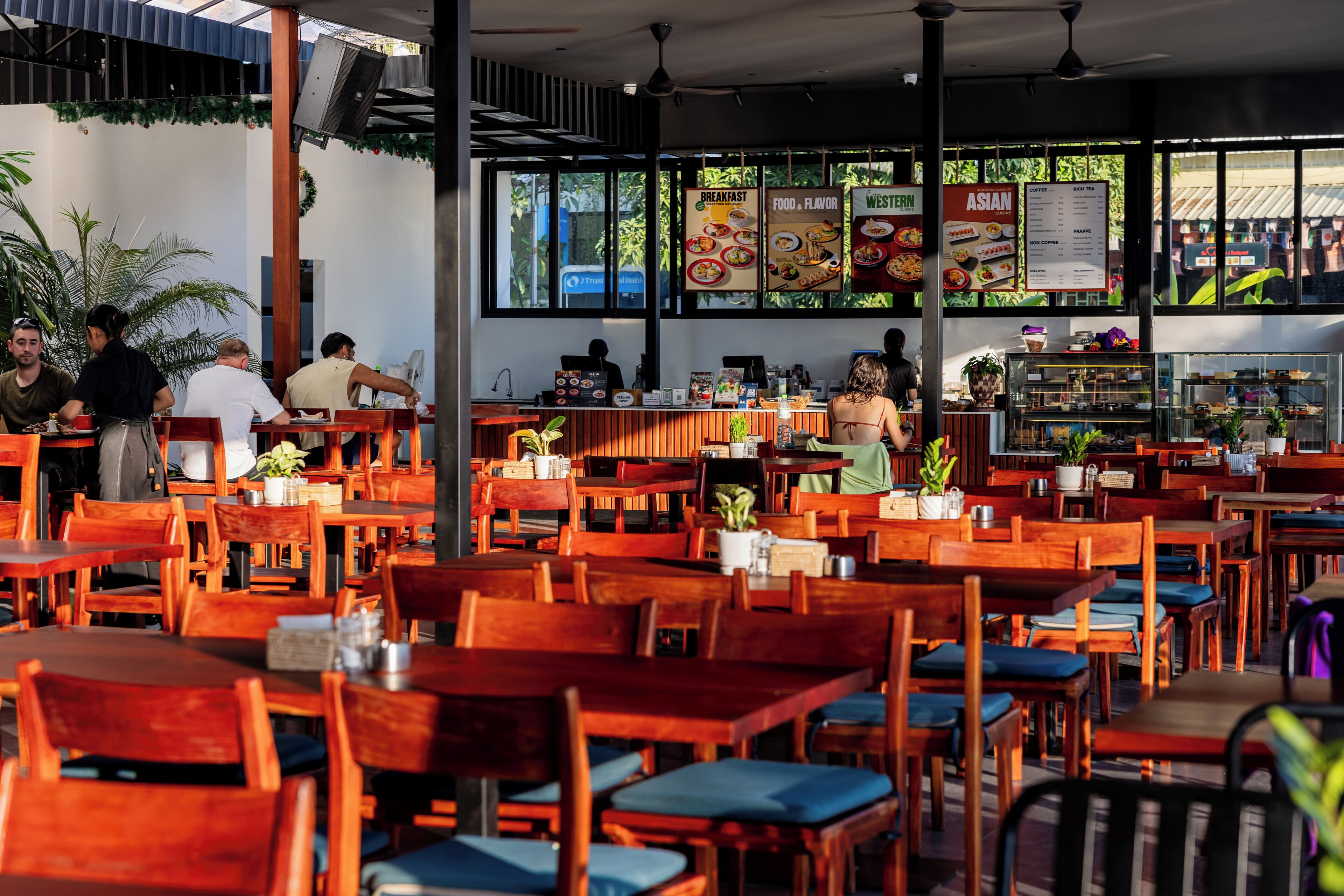 Un restaurant avec des tables et des chaises en bois, un tableau affichant le menu et un comptoir à café.