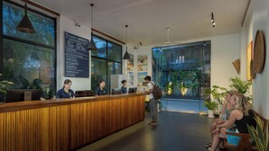 Zona de recepción con un mostrador de madera, un ventanal con vistas a zonas verdes e información de servicios en una pared.