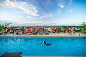 A pool area with lounge chairs and a swimmer. - Onederz Hostel Siem Reap (Siem Reap)