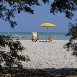 Na praia, espreguiçadeiras, guarda-sóis