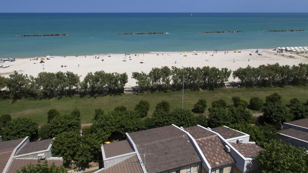 A beach with clear skies, a sandy shore, and a few boats. - Residence Casabianca (Fermo)