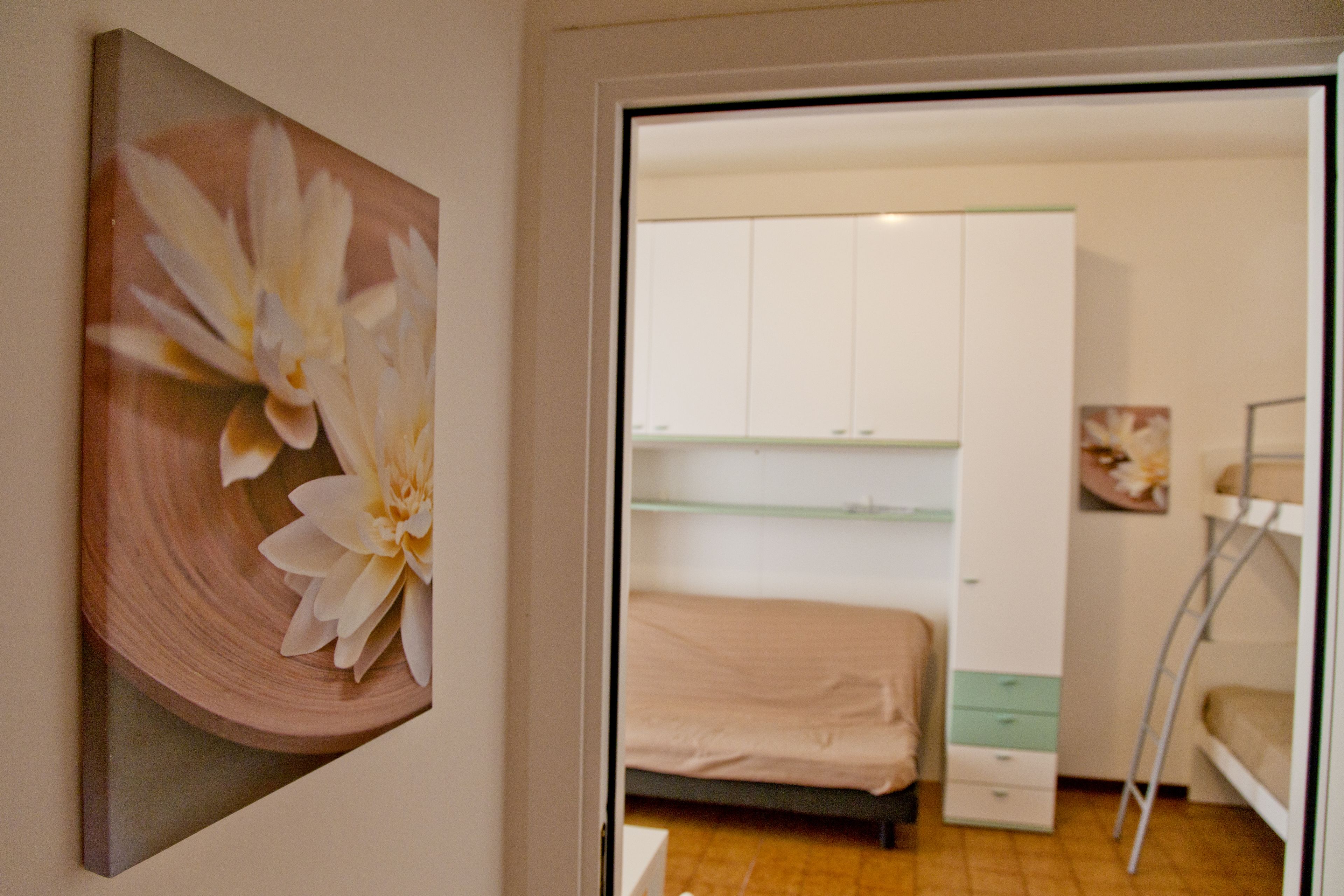 A bedroom with a bed, a wardrobe, and a painting of flowers.
