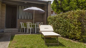 A patio with a striped umbrella, a lounge chair, and a table with chairs. - Residence Casabianca (Fermo)