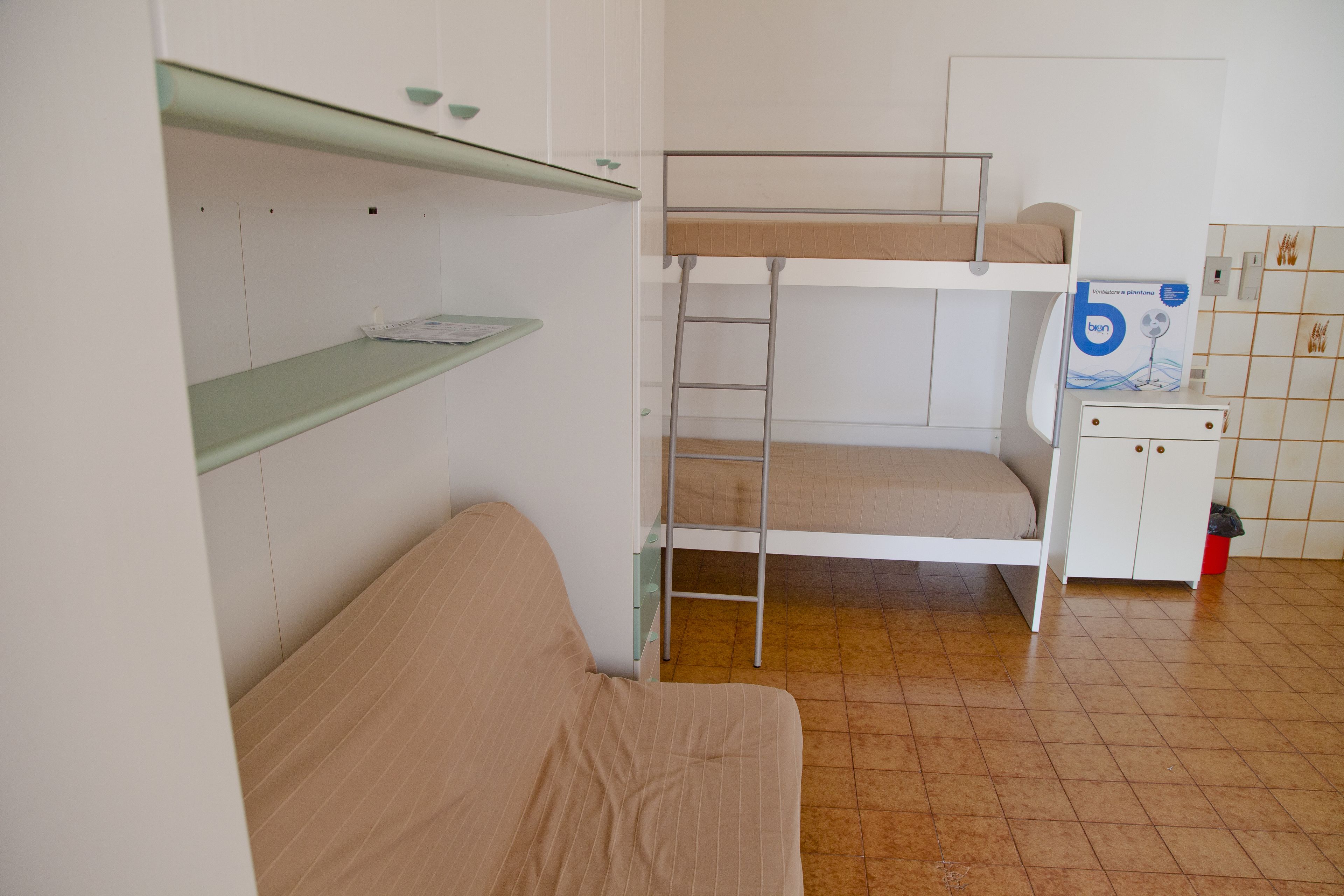 Habitación con literas, un pequeño armario y una estantería.