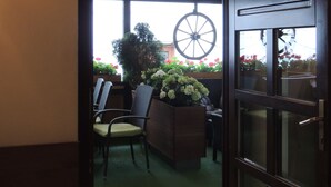 An interior view of a room with a wooden door, a large window with a view of a garden, and a wall decorated with mounted animal heads. - Hotel Club (Kezmarok)