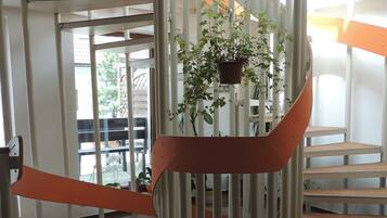 A spiral staircase with a brown carpet, white railings, and a hanging plant.
