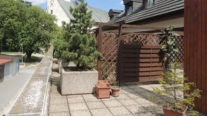 A courtyard with a large tree, a wooden gate, and a building with a tower. - Hotel Club (Kezmarok)