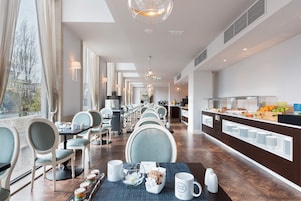 Un espace de restauration d’hôtel avec des tables, des chaises et un buffet.