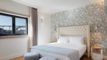 Un dormitorio con una cama grande, una ventana con vista a un puente y un papel tapiz floral.
