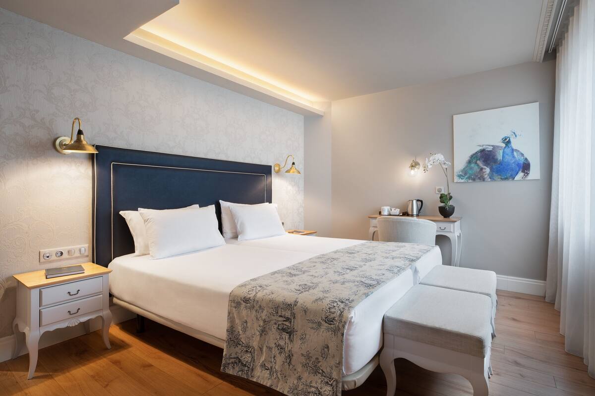 A modern bedroom with a large bed, bedside tables, a desk, and a chair.