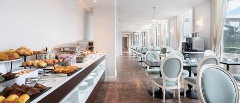 A buffet area with various food items and a seating area with tables and chairs.