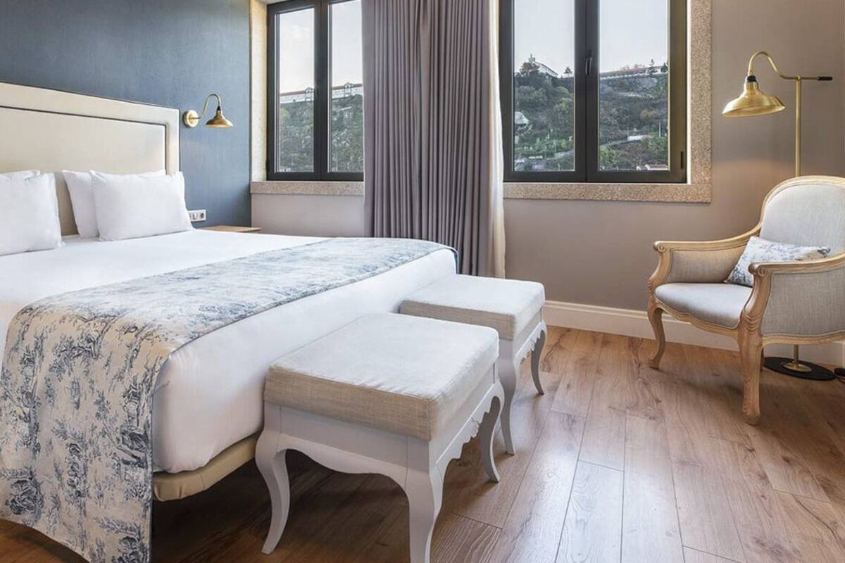 A hotel room with a large bed, a chair, and a view of the outdoors.