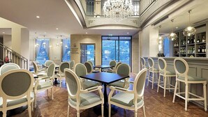 A spacious dining area with high ceilings, a chandelier, and a view of the city. - Eurostars Porto Douro (Porto)